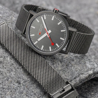 Gray mesh watch with a gray dial on a stone surface